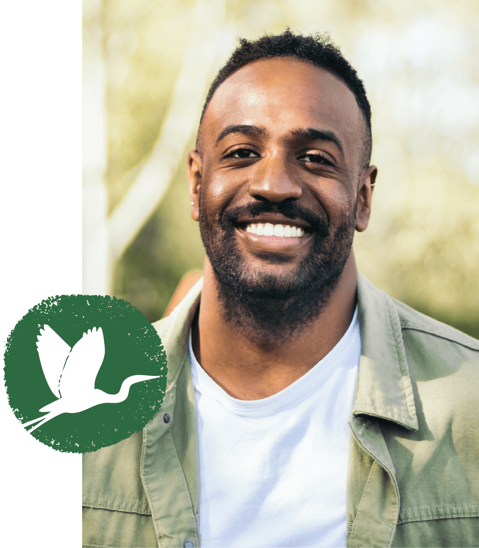 A man outdoors, with the St. Christopher's heron emblem