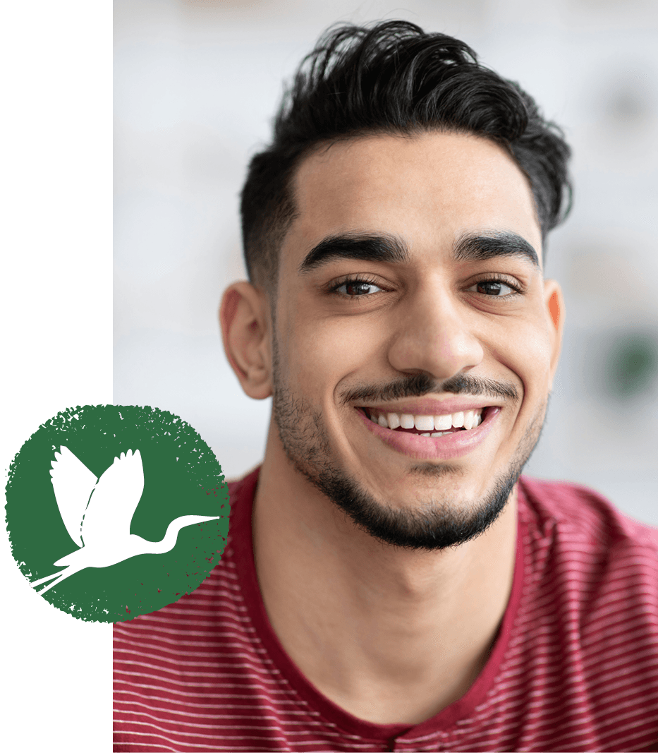 A smiling man, with the St. Christopher's heron emblem